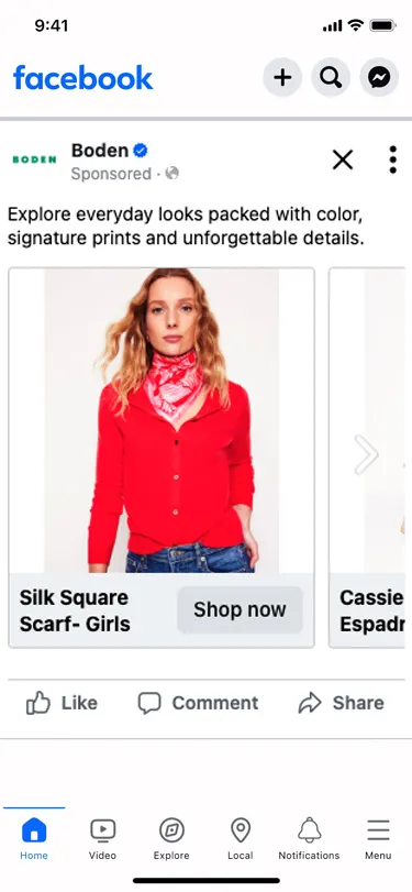 A Boden dynamic catalog ad in the mobile Facebook feed, with the copy "Explore everyday looks packed with color, signature prints and unforgettable details" above a swipeable product carousel; the first card shows a model in a red cardigan and pink printed scarf, labelled Silk Square Scarf - Girls with a Shop now button, and the next card is already sliding into view